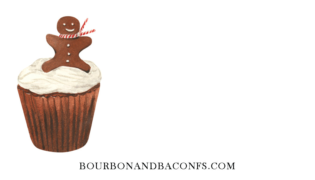 Red velvet cupcake with white frosting and a gingerbread man on top, featuring the website 'bourbonandbaconfs.com'.